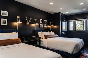 Une chambre d’hôtel avec deux lits, un mur de couleur sombre et des tableaux encadrés.