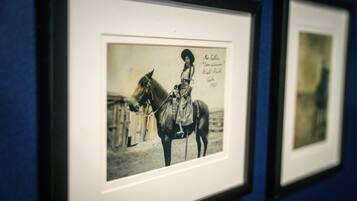 A framed photograph of a woman on a horse, with a caption indicating it is from 1923.