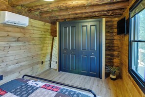 A log cabin room with a bed, a door, a TV, and a window. - Fairhaven Harbor-Front Gem - Steps From the Water! (Fairhaven)