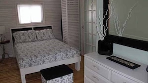 Un dormitorio con cama, cómoda, espejo y ventana.