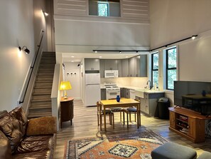Uma cozinha moderna com área de jantar, escada e sala de estar com TV e centro de entretenimento.