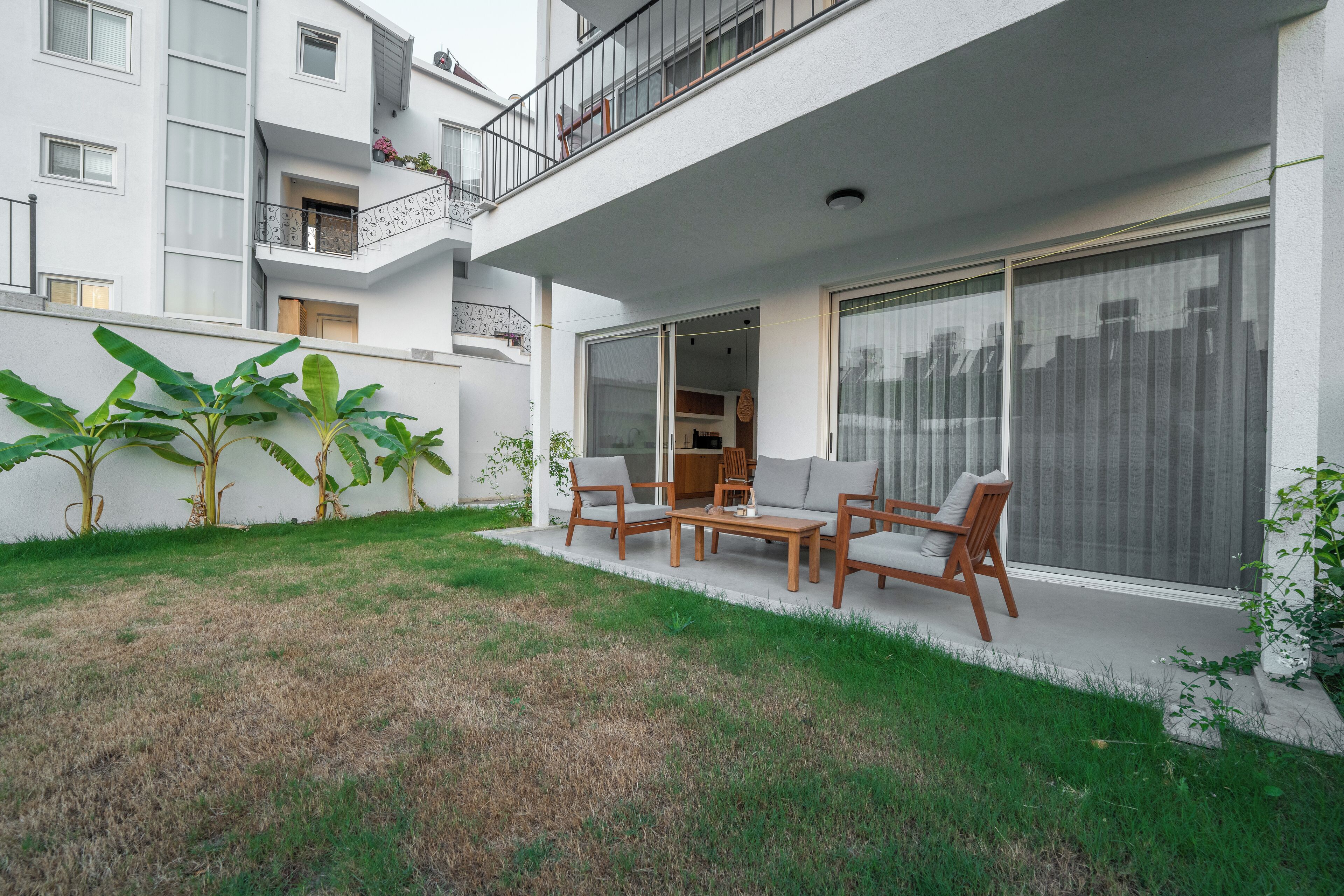 A modern apartment with a balcony, outdoor seating, and large windows.