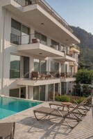 Un hotel de varios pisos con piscina, mobiliario exterior y balcones.
