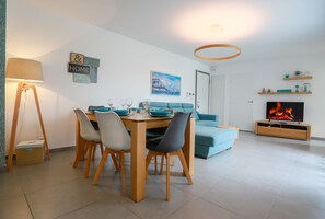 Ein modernes Wohnzimmer mit Essbereich, einer Couch, einem Fernseher und einem Kamin.