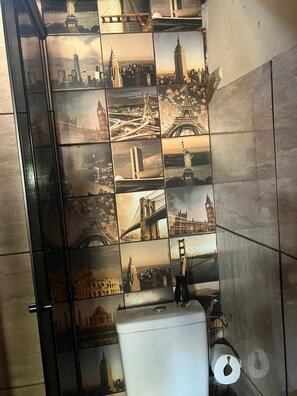 A bathroom with a tiled wall featuring various famous landmarks. - Chalé Refúgio 1 (Corumba de Goias)