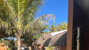A tropical outdoor area with a thatched-roof structure, palm trees, and a patterned floor. - Chalé Refúgio 1 (Corumba de Goias)