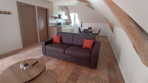 Ein gemütlicher Wohnbereich mit einer Couch, einem Esstisch und einer Küche im Hintergrund.