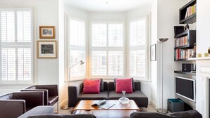 Ein modernes Wohnzimmer mit einer Couch, Sesseln, einem Couchtisch und einem Bücherregal.