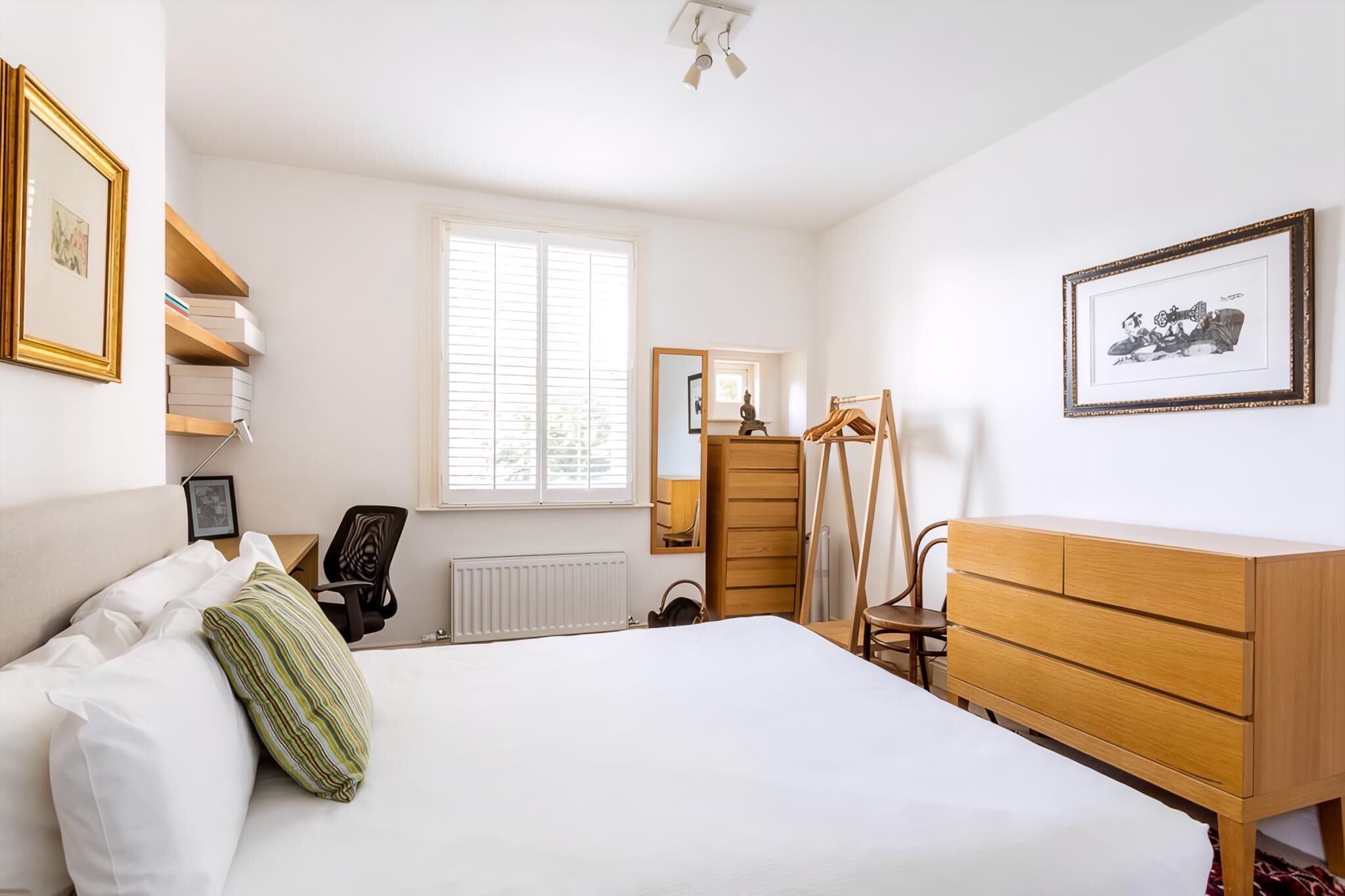 A bedroom with a bed, a dresser, a chair, a desk, and a window.