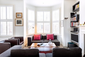 A living room with a sofa, armchairs, a coffee table, and a bookshelf.