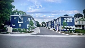 Una hilera de casas urbanas azules con un paseo central, un hidrante y una tapa de alcantarilla en la calle.