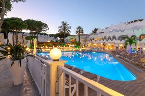 En swimmingpool med solstolar och ett vitt staket.