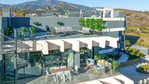 A modern building with a glass facade, outdoor seating area, and a view of mountains. - OASIS 325 penthouse with panoramic views (Estepona)