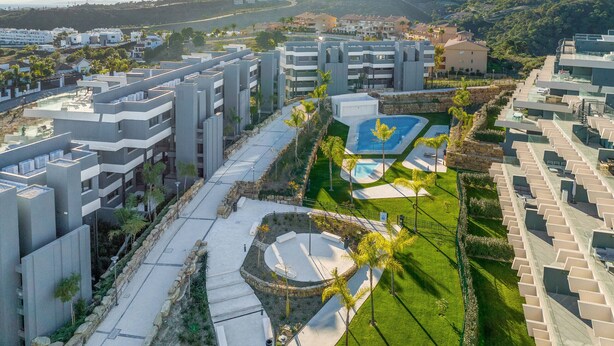 A modern residential complex with multiple apartment buildings, a central courtyard with a swimming pool, and a view of a mountainous landscape. - OASIS 325 penthouse with panoramic views (Estepona)