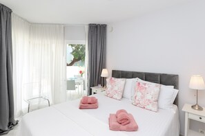 A hotel room with a large bed, two pillows, a nightstand with a lamp, a chair, and a view of the outdoors. - Ground-floor apartment in Elviria del Sol (Marbella)
