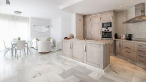 A modern kitchen with a central island, built-in oven, and stainless steel appliances. - Elviria del Sol ground floor apartment (Marbella)
