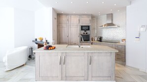 A modern kitchen with a central island, built-in appliances, and a white color scheme. - Elviria del Sol ground floor apartment (Marbella)