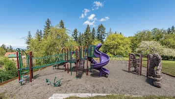 Une aire de jeux avec un toboggan violet et des structures d’escalade.