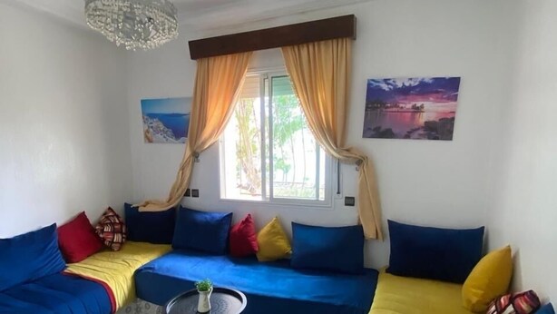 A living room with a blue sofa set, a small round table, and a chandelier.