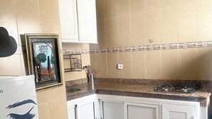 A kitchen with white cabinets, a gas stove, and a patterned rug.