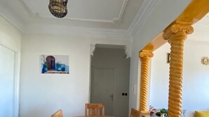 A dining area with a wooden table and chairs, a chandelier, and a painting on the wall.