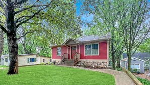 A single-story house with a red exterior, a front porch, and a well-maintained lawn.