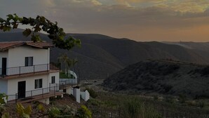 A two-story building with a balcony, surrounded by a vineyard and hills in the background. - Viñas del Castillo Hotel Boutique (Ensenada)