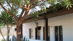 A building with a white exterior, large windows, and a hanging planter. - Viñas del Castillo Hotel Boutique (Ensenada)