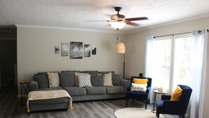 A living room with a grey sofa, a round coffee table, and a ceiling fan.