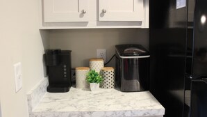 A kitchen with white cabinets, a black refrigerator, a coffee maker, and decorative containers.