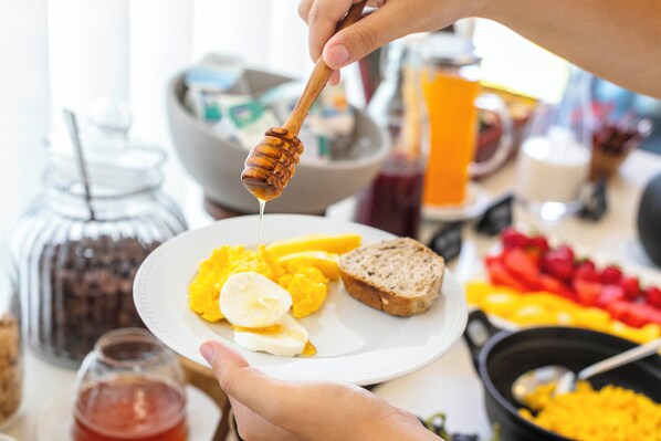 Une assiette de petit-déjeuner avec des œufs brouillés, une tranche de pain grillé et un verre de jus d’orange.