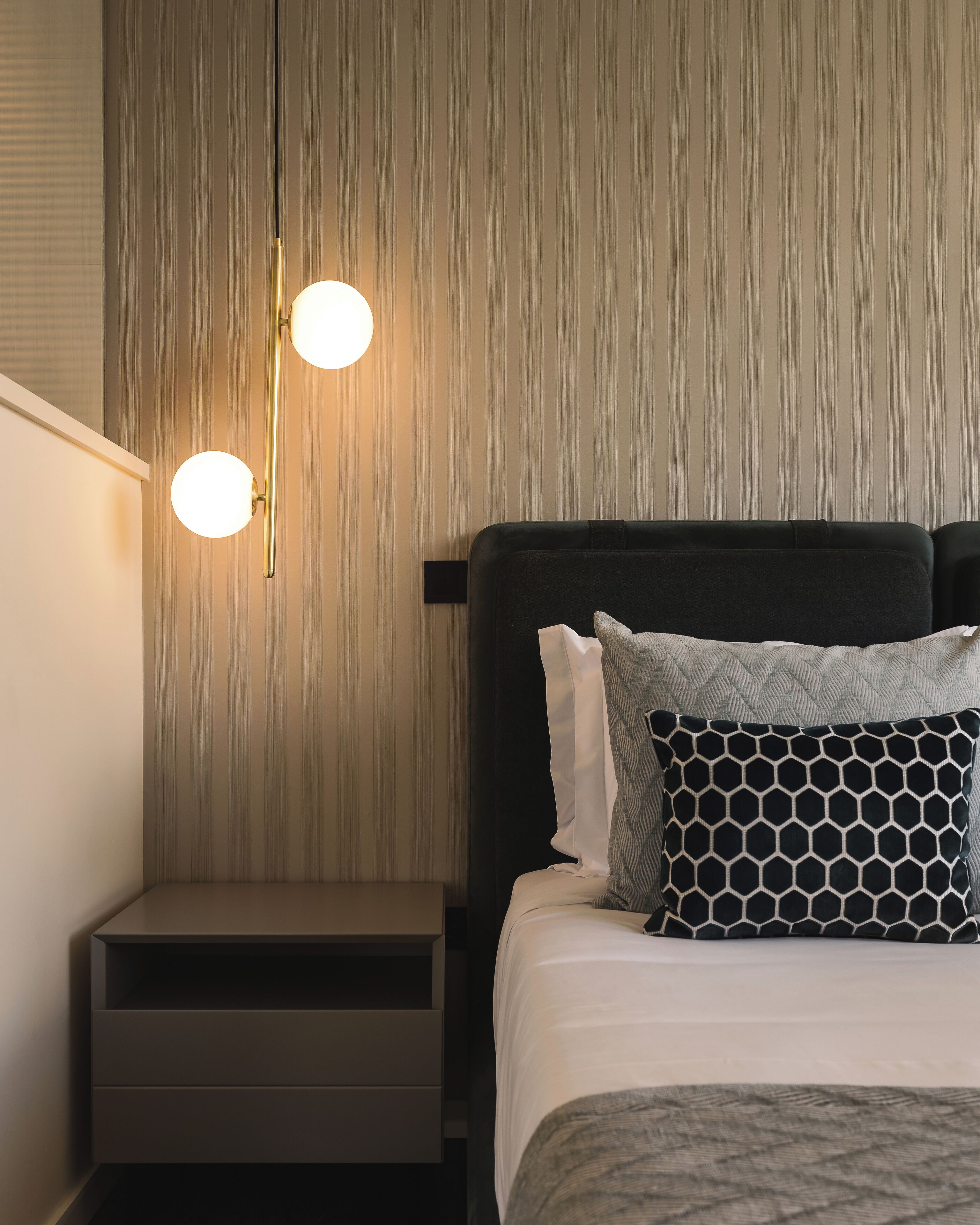 Een keurig opgemaakt hotelkamer met een bed, nachtkastjes en een wandlamp.