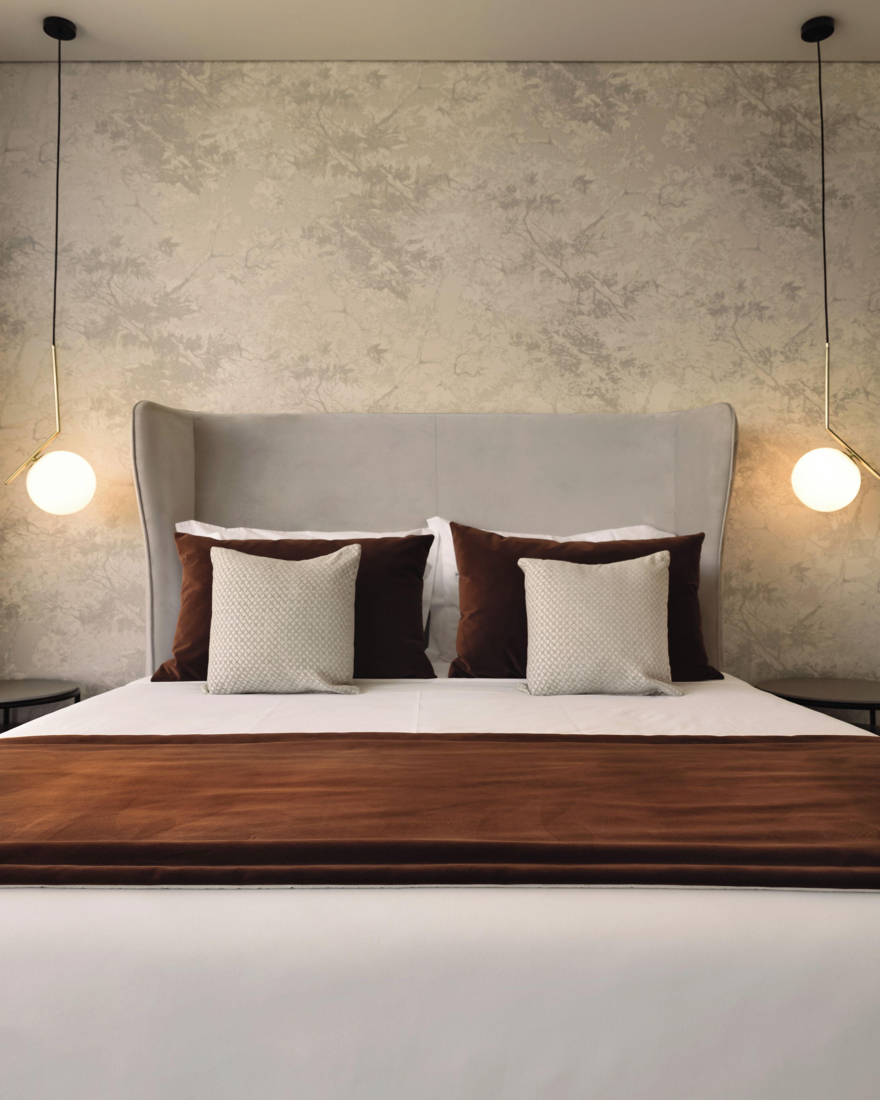 A modern bedroom with a large bed, two nightstands, and a textured wall.