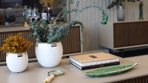 A well-organized desk with two white ceramic pots, a book, a magnifying glass, and a green decorative plate. - Quinta Vale de Lobos Douro (Armamar)