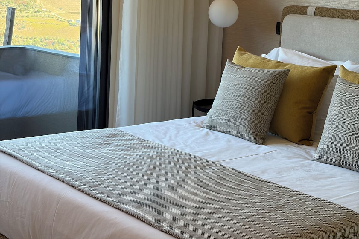 Ein Hotelzimmer mit einem großen Bett, Blick auf die Landschaft und einer modernen Lampe.