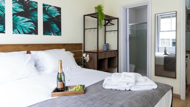 A hotel room with a bed, a bedside table with a bottle of champagne and glasses, a tray with grapes, and a set of towels. - Copacabana  (Rio de Janeiro)