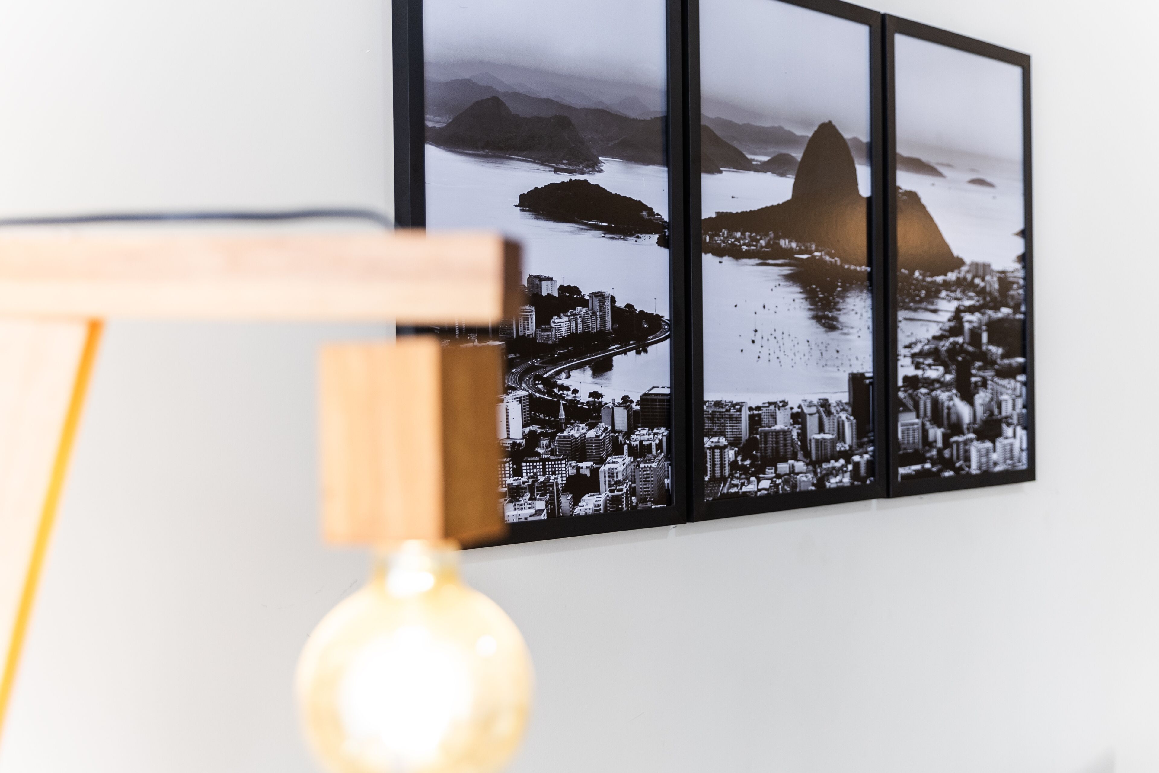 A framed cityscape photograph on a wall, with a light bulb in the foreground.