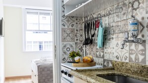 A kitchen with a granite countertop, a sink, a stove, and a hanging rack for utensils. - Copacabana  (Rio de Janeiro)