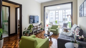 A modern living room with a herringbone floor, green sofas, a coffee table, and a TV on the wall. - Copacabana  (Rio de Janeiro)