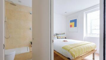 Un dormitorio con cama, ventana y zona de ducha.