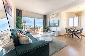 Ein modernes Wohnzimmer mit einer Couch, einem Essbereich und einem Balkon mit Blick.