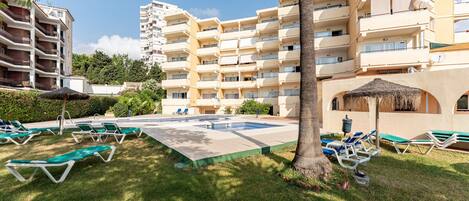 A hotel with multiple balconies, a swimming pool, and sun loungers.