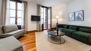 A modern living room with a sofa, a green couch, a round coffee table, and a flat-screen TV. - SOUL BEACH apartment (PARKING INCLUDED) (San Sebastián/Donostia)