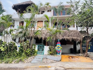 Experience the tropical charm of this multi-story villa with a thatched roof, lush greenery, and a pool.