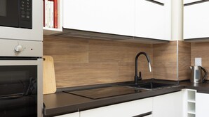 A modern kitchen with white cabinets, a black countertop, a built-in oven, a black faucet, and a coffee maker. - "Ci vuole leggerezza" Apartment (Bologna)