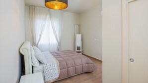 A bedroom with a bed, a white headboard, a hanging lamp, a radiator, and a door. - "Ci vuole leggerezza" Apartment (Bologna)