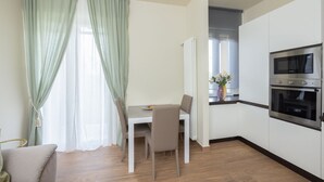 A modern kitchen with white cabinets, a built-in oven, and a dining area with a table and chairs. - "Ci vuole leggerezza" Apartment (Bologna)