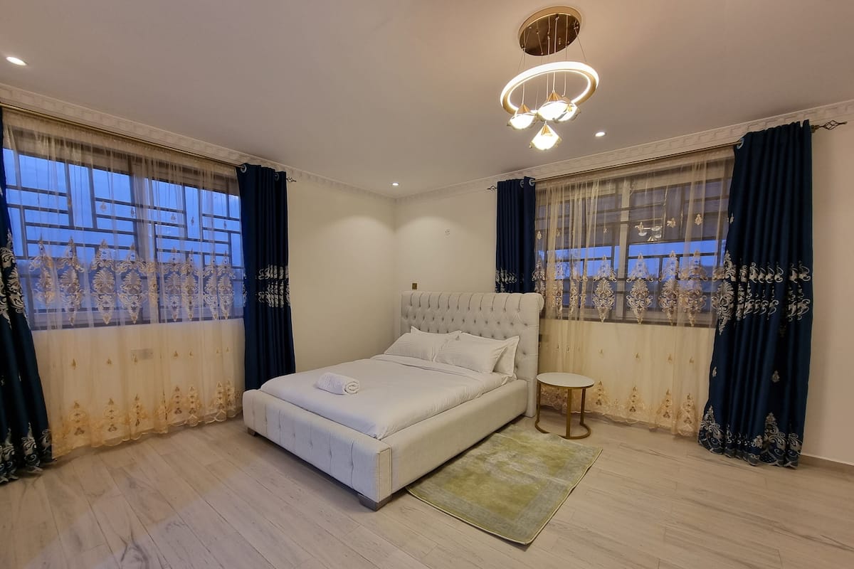 Une chambre moderne avec un grand lit, une table ronde et un lustre.