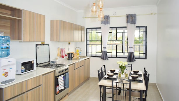 Une cuisine moderne avec des meubles en bois, une cuisinière, un four à micro-ondes et un coin repas comprenant une table et des chaises.