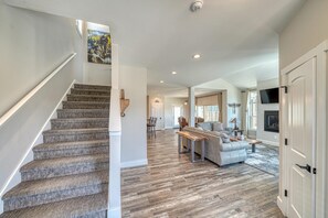 A spacious living area with a staircase, a fireplace, and a large TV. - Silver Vault- PET FRIENDLY-Brand New Railyard home W/ HOT TUB- minutes to Copper & Ski Cooper! (Leadville)